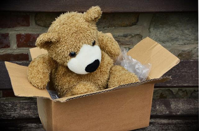 A teddy bear in a cardboard box. 
