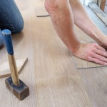 A person holding a pencil and measuring their floor using some home renovation tips.