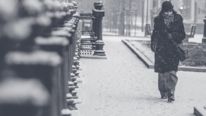 A woman moving through the blizzard in a city.