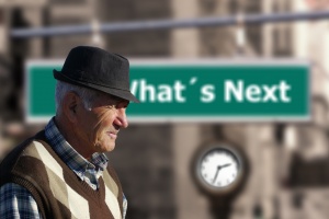 An elderly man with a hat walking down the street.