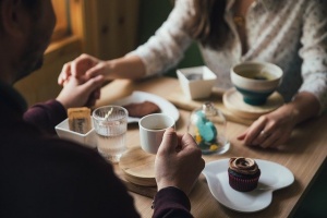 A couple enjoying a coffee and cupcakes.
