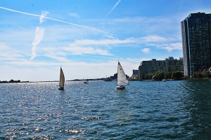 A few boats near Lake Ontario shore with the building in the background.