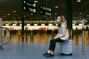A woman at the airport sitting on the luggage.
