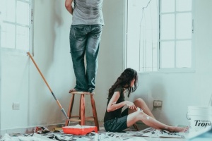 Two people painting their walls and trying to improve their home in accordance with Overland Park's real estate trends.