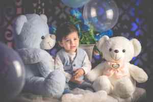 A boy sitting between two huge teddy bears