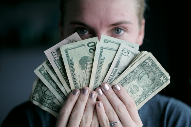 a woman holding money to pay ex-pat taxes in the US