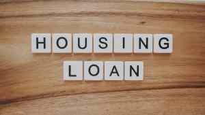 housing loan spelled out on a wooden surface with white block.