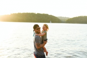 A man holding his daughter at a lake