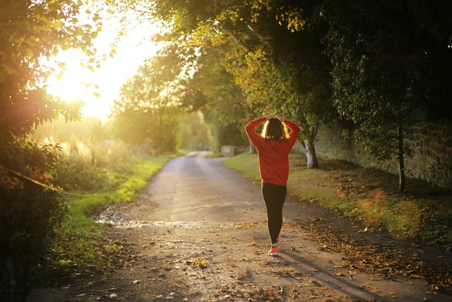 A woman in a red sweatshirt jogging during sunset