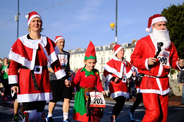 A family with kids, all dressed up as Santas, participating in an event