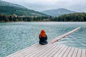 A girl sitting by a lake.